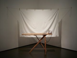 Betye Saar, I’ll Bend But I Will Not Break, 1998. Mixed media tableau: vintage ironing board, flat iron, metal chin, white bed sheet, six wooden clothespins, cotton, clothesline and one rope hook, 80 x 96 x 36 in (203.2 x 243.8 x 91.4 cm), Los Angeles County Museum of Art, Gift of Lynda and Stewart Resnick through the 2018 Collectors Committee, © Betye Saar