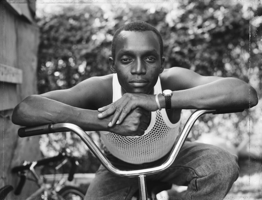 Dawoud Bey, A Young Man Resting on an Exercise Bike, Amityville, NY, 1988.