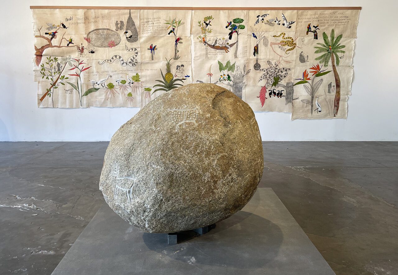 Front: Denilson Baniwa in collaboration with Francineia Baniwa, Itá, 2023. Bas-relief stone carving. Courtesy of the artist and A Gentil Carioca. Back: Denilson Baniwa, Kwema, 2023, Dawn, Site-specific installation. Commissioned by Fundação Bienal de São Paulo for the 35th Bienal.